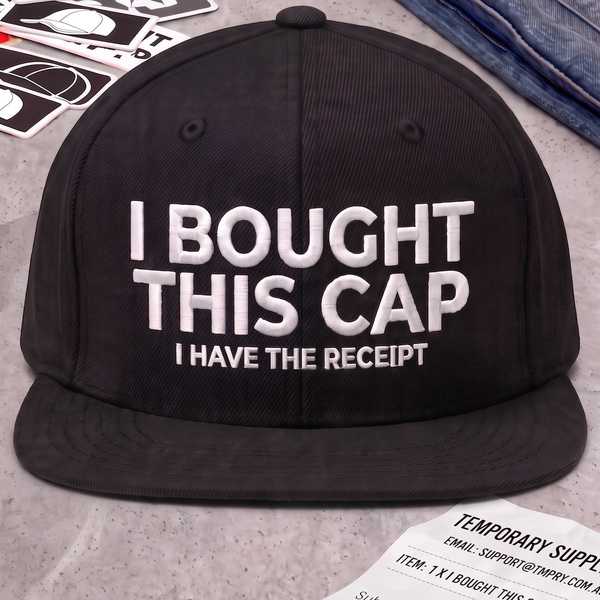 A black snapback cap with white text reading 'I BOUGHT THIS CAP, I HAVE THE RECEIPT' is displayed prominently in front of the cap.